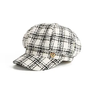 Detailed view of the checkered tweed newsboy hat with a golden heart accent.