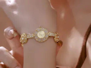 Close-up view of a luxury gold flower-shaped bracelet watch adorned with crystals