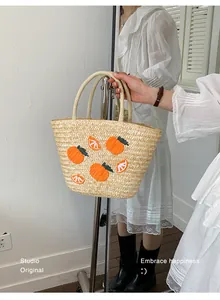 Detailopname van een handgeweven strooien tas met levendige oranje borduur