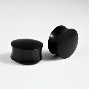 Close-up detail of solid black ebony wood hourglass ear plugs for ear lobe stretching.