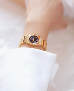 Gedetailleerde close-up van een elegant gouden dameshorloge met strass-bezel en zwarte wijzerplaat