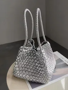 Detailed view of a silver metallic woven basket bag with braided handles on a table.