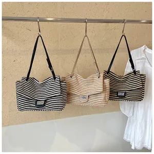 Juego de tres bolsos de hombro de paja a rayas en variantes negro, caqui y bronceado.
