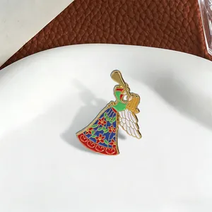 Primo piano di una spilla in smalto a forma di angelo floreale con tromba dorata.