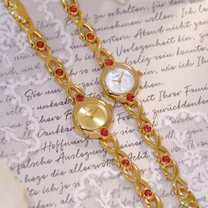 Elegante reloj vintage dorado para mujer con piedras rojas y fondo de encaje retro