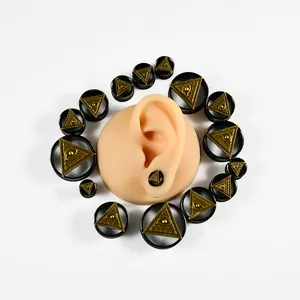 Detalle de expansores de oreja en acero negro con diseño dorado del ojo de la providencia