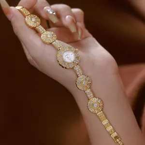 Exquisite gold floral bracelet watch with crystals presented on a female hand model.