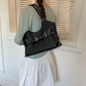 Detailed view of a black underarm bag with decorative belt strap and silver eyelets.