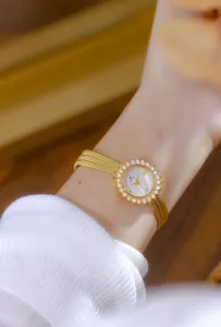 Detalle de un reloj vintage dorado con bisel de pedrería en forma de sol en la muñeca
