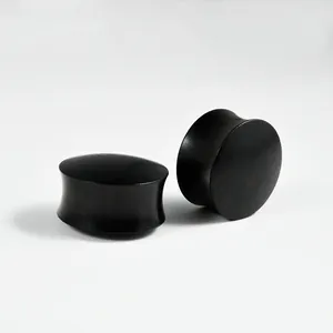 Close-up of solid ebony wood saddle ear gauge plugs with smooth matte finish