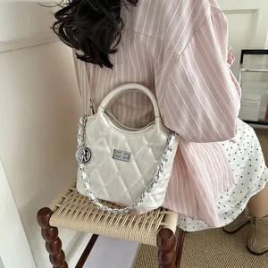 Detailed view of cream quilted crossbody bucket bag with chain strap and coin charm