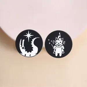 Detailed view of circular black and white metal enamel pins with wizard cat design