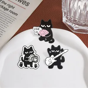 Set of three quirky black cat enamel pins featuring guitar, camera and brain motifs.