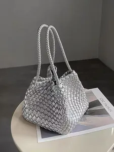 Close-up of silver woven bucket bag with intricate handmade texture on minimalist table.