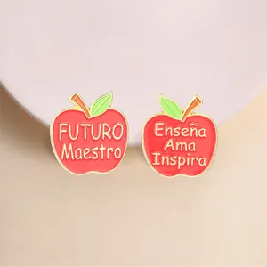 Detailed macro view of red apple enamel pins with Spanish teacher appreciation text