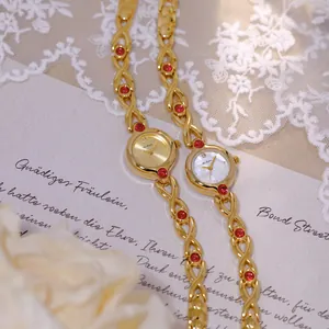 Primer plano del reloj de oro retro francés Bee Sister con piedras rojas y encaje
