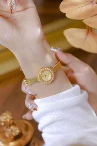 Primer plano de un elegante reloj vintage dorado de sol con diamantes en la muñeca