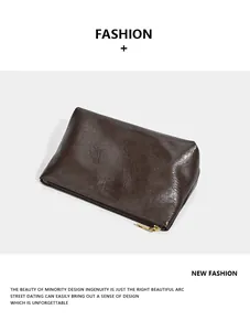 Detailed macro shot of a vintage dark brown leather pouch featuring a smooth gold zipper