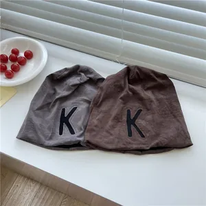 Due berretti slouchy sottili da donna con toppa lettera K nei colori grigio e marrone.