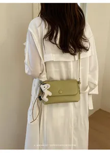Vista posteriore dettagliata di una donna con una borsa a tracolla verde chiaro minimalista