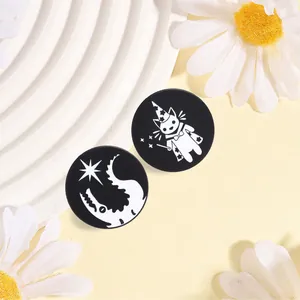 Close-up of black and white magic pins featuring a cute wizard cat and crescent moon design