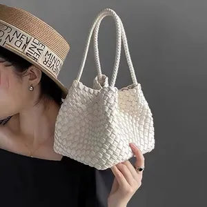 Detailed close-up of a white hand-woven bucket handbag featuring intricate weave textures