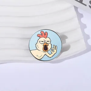 Close-up of a round metal brooch featuring a funny cartoon rooster making an OK gesture.