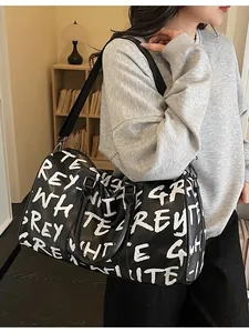Stylish large capacity travel duffel bag featuring white graffiti letter print for women.