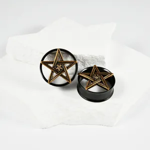 Detalle de expansores de oreja de acero negro con diseño de estrella de pentagrama