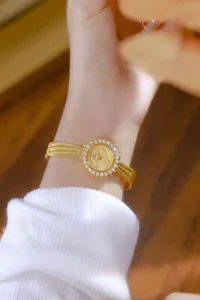 Primer plano de un elegante reloj dorado con un bisel de diamantes en la muñeca