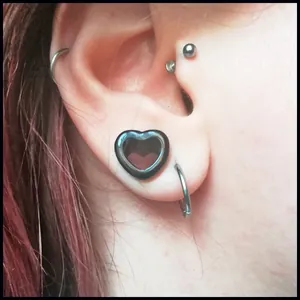 Nahaufnahme einer schwarzen herzförmigen Acryl-Ohrlehre in einem Ohrläppchen-Piercing