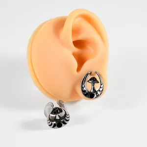 Detailed view of mushroom-themed stainless steel U-shaped ear gauges on model