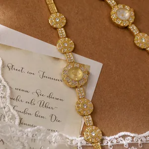 Elegant vintage golden flower bracelet watch with crystals on a retro background.