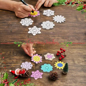 Detailopname van DIY kerstsneeuwvlokornamenten die worden ingekleurd op houten tafel