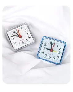 Close-up of two minimalist square analog alarm clocks in blue and white finishes.