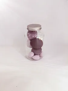 Macro detail of various purple beauty sponges inside a transparent jar with metallic lid.