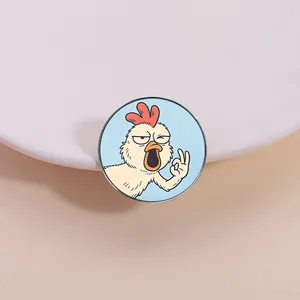 Macro view of a funny hand-drawn cartoon rooster enamel pin featuring an OK hand gesture
