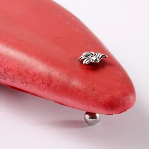 Primer plano detallado de un piercing de lengua de araña de acero inoxidable plateado.
