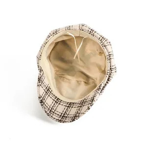 Interior view of a beige checkered tweed newsboy cap showing lining and drawstring