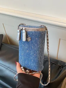 Stylish blue denim crossbody phone bag featuring a silver chain and camellia charm