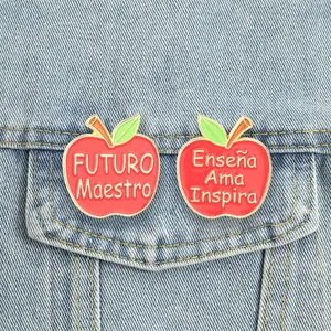 Close-up view of red apple metal pins with Spanish inspirational text for teachers
