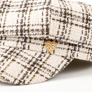 Close-up of a stylish tweed newsboy cap featuring a golden heart-shaped quilted button detail