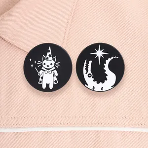 Close-up of black and white circular enamel pins featuring wizard cat and star crocodile