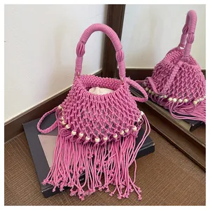 Detailopname van een roze handgemaakte boho geweven tas met lange franjes en witte kralen