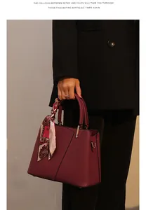Detailed view of the elegant red leather handbag showcasing exquisite texture and scarf decor.