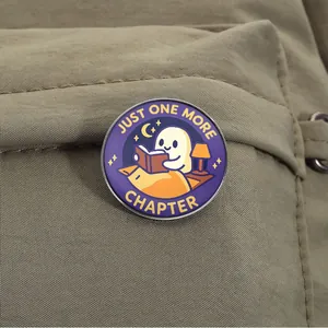 Detailopname van een schattige spookspeld met de tekst 'Just One More Chapter' op rugzak