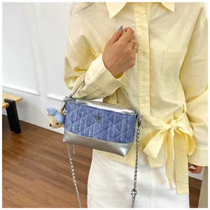 Dettaglio di una borsa in denim trapuntato blu con finiture argentate e catena.