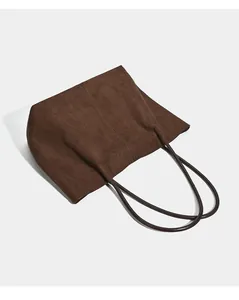 Detailed view of a dark brown suede tote bag lying flat against a light grey background.