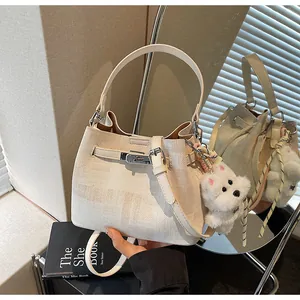 Detailansicht der cremefarbenen Eimertasche mit Silberschnalle und Plüschhund