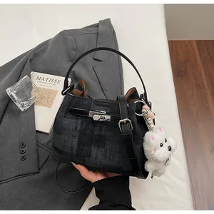 Detailansicht der schwarzen karierten Pendler-Handtasche mit süßem weißen Plüschhund-Anhänger